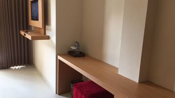 A modern hotel room with a wooden console table, a mounted television, and a red stool.
