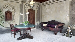 Una habitación con una mesa redonda, sillas, un sofá y una estatua decorativa.