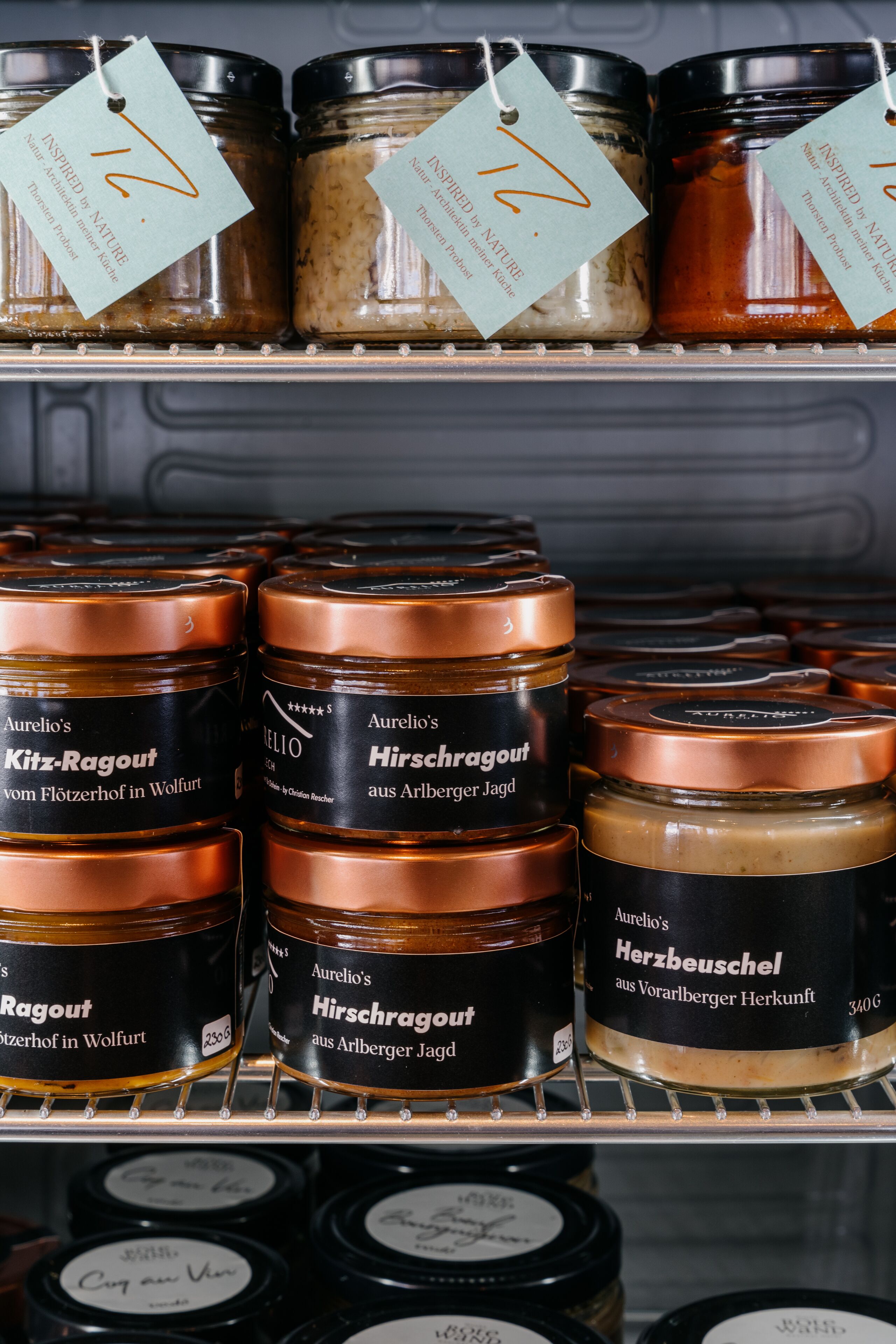 Shelves stocked with jars of food products, each labeled with the brand name and product type.