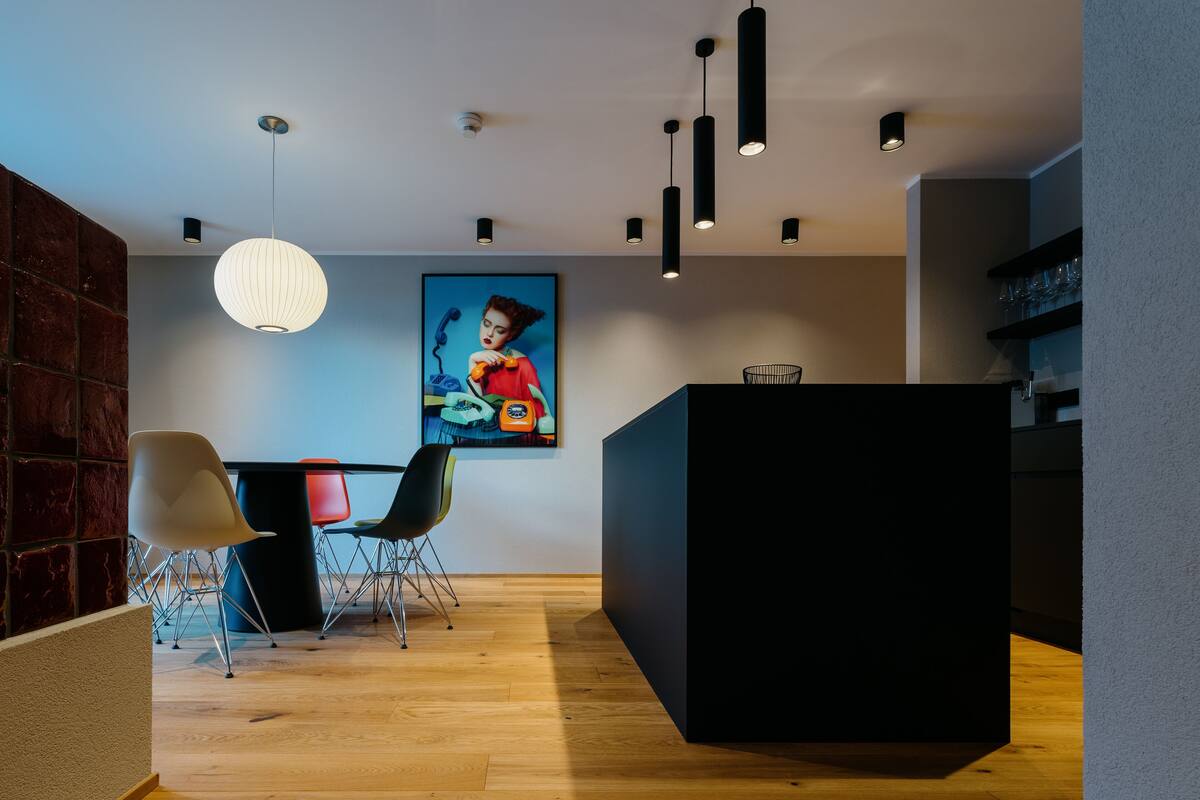 Un interno moderno con pavimento in legno, una reception nera e un quadro colorato appeso al muro.