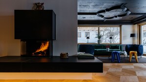 A modern living room with a fireplace, a sofa, and a coffee table. - Appart Hotel Knappaboda (Lech am Arlberg)