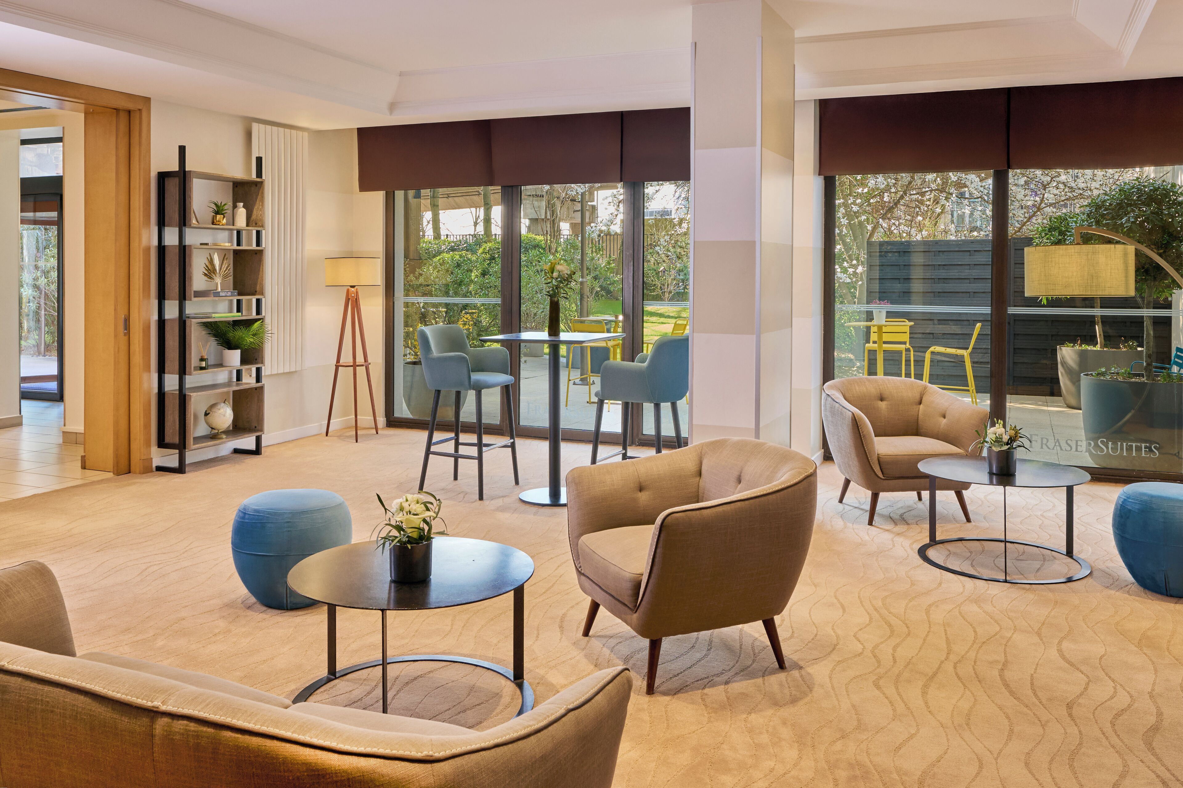 A modern living room with a sofa, armchairs, a coffee table, and a bookshelf.