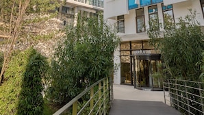 A modern hotel with a glass facade, a prominent entrance, and a surrounding landscaped area.