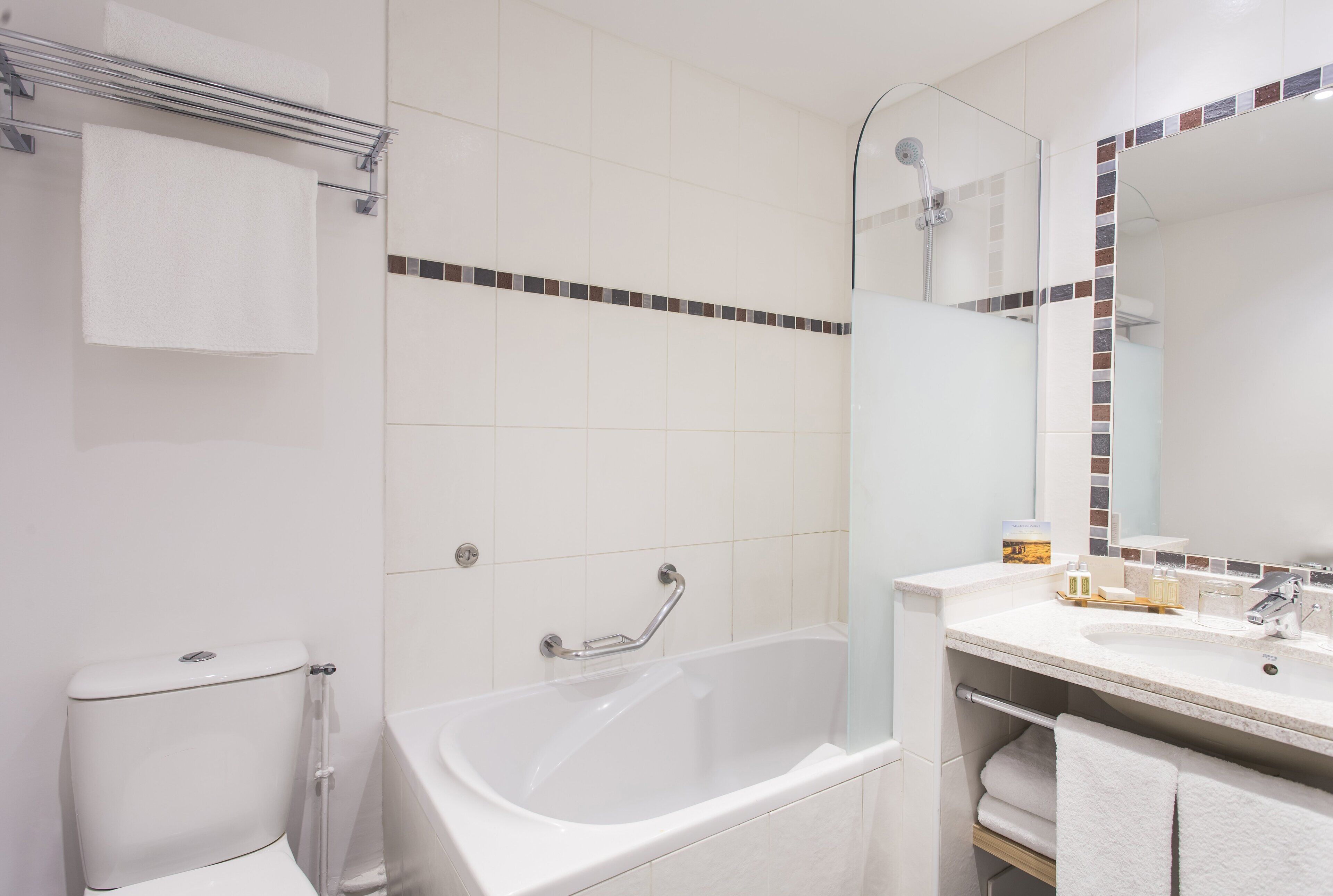 A modern bathroom with a bathtub, a toilet, a glass shower enclosure, and a vanity with a mirror.