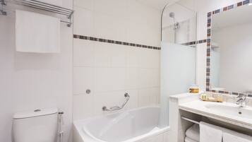 A modern bathroom with a bathtub, a toilet, a glass shower enclosure, and a vanity with a mirror.