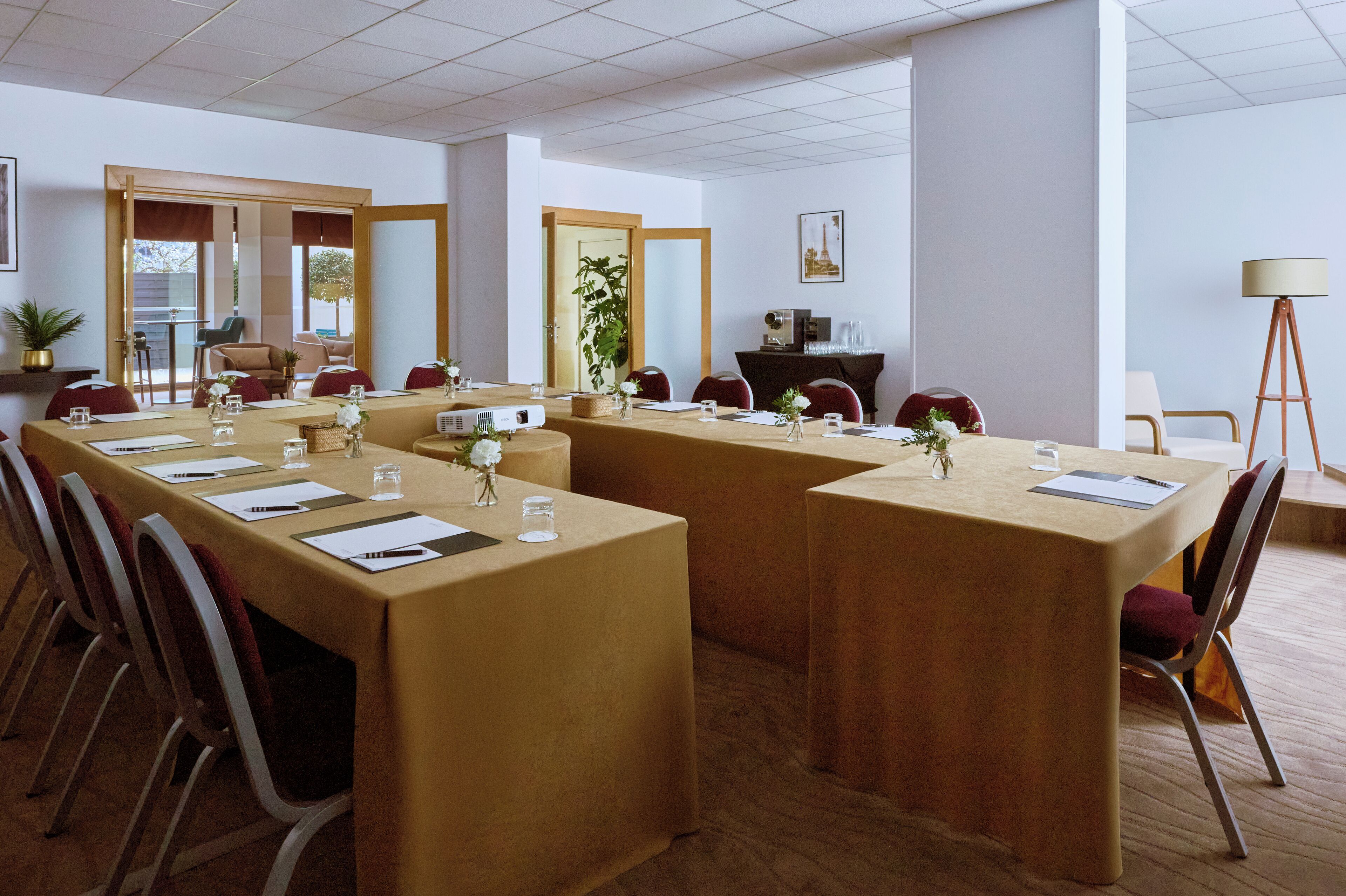 Une salle de conférence équipée de plusieurs tables, de chaises et d’un projecteur.