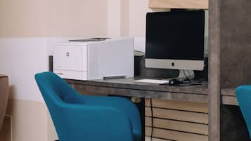 Un espacio de trabajo con un ordenador de escritorio, una impresora y sillas color turquesa.