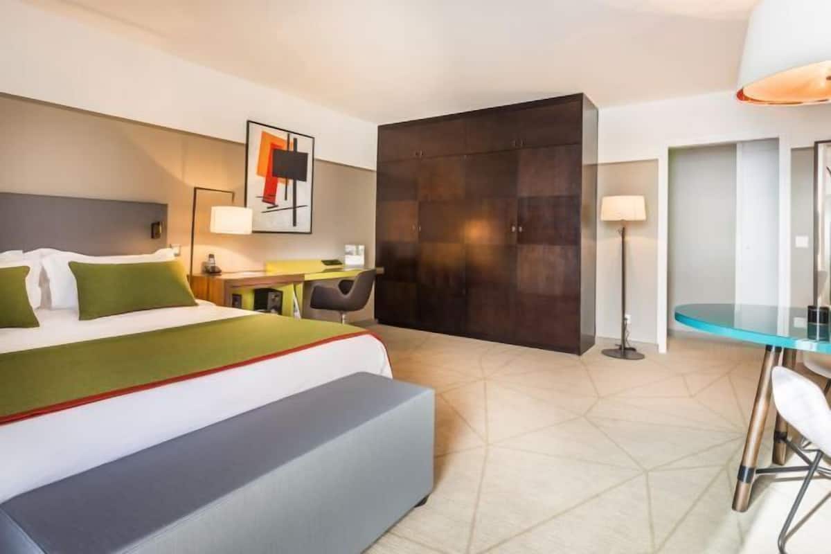 Ein modernes Hotelzimmer mit Bett, Schreibtisch, Stuhl und Kleiderschrank.