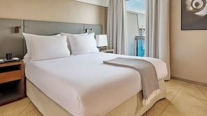 A hotel room with a large bed, a nightstand, a lamp, and a window with curtains.