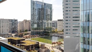 A modern building with a glass facade, a rooftop pool, and a view of a cityscape including a tall building labeled "Allianz".