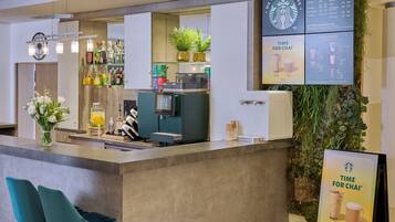 Un espace bar moderne doté d’une machine à café, de sièges et d’un tableau affichant le menu.