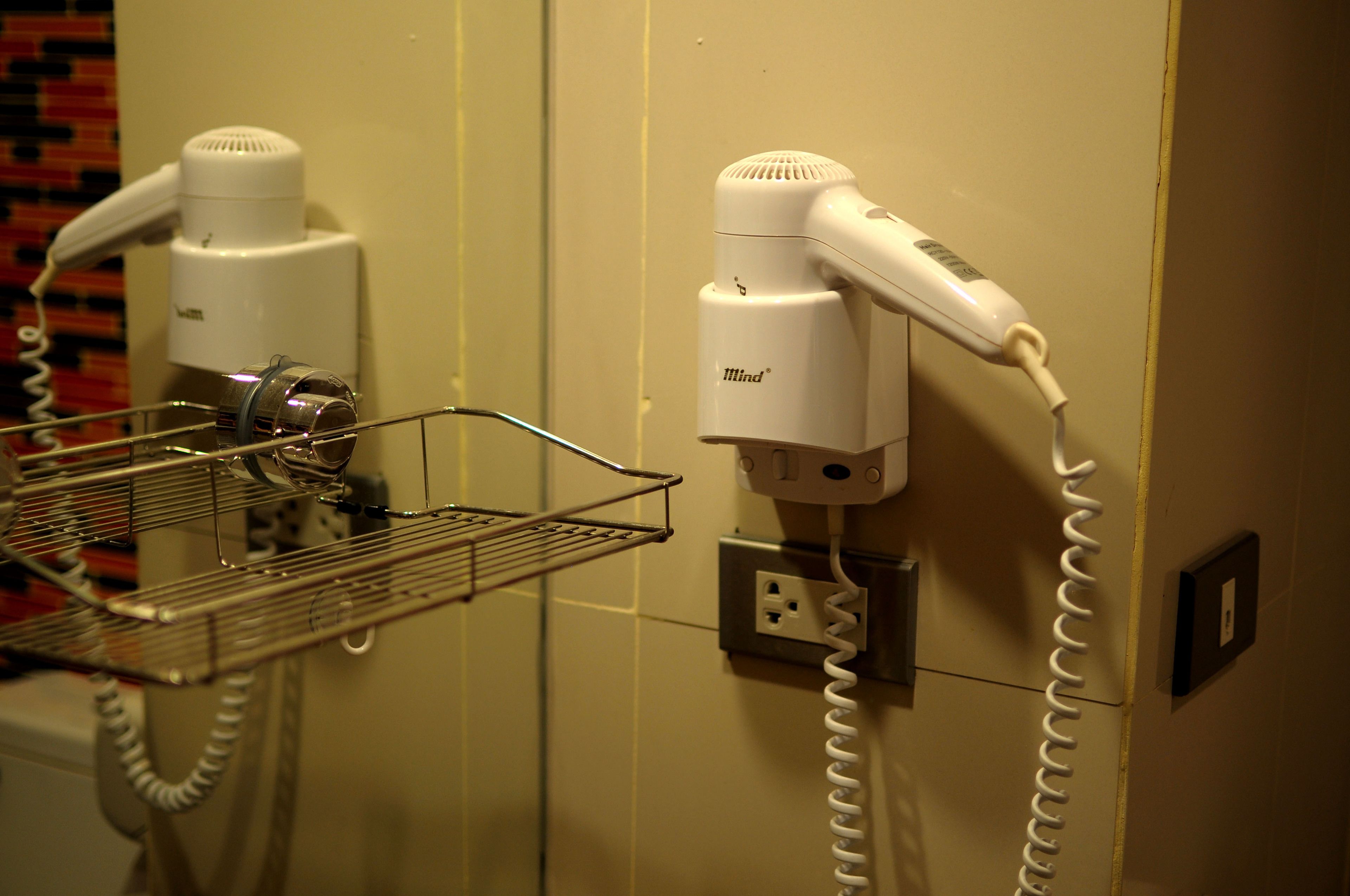 A hairdryer and a vacuum cleaner on a wall-mounted rack in a bathroom.