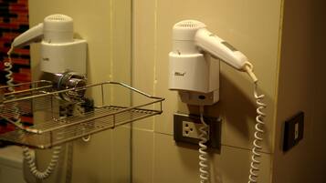 A hairdryer and a vacuum cleaner on a wall-mounted rack in a bathroom.