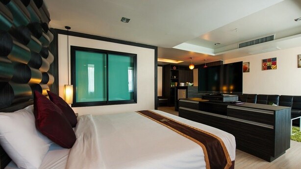Une chambre d’hôtel moderne, dotée d’un grand lit, d’un bureau et d’une télévision.