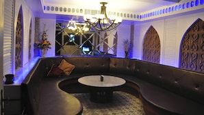 Un coin salon accueillant avec une table ronde, des bancs rembourrés et un lustre décoratif.