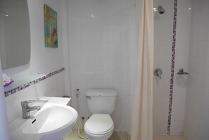 A bathroom with a white sink, toilet, and shower.