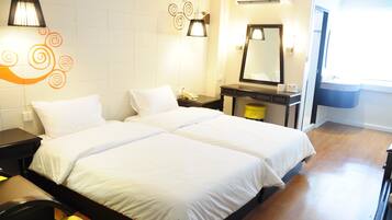 A hotel room with two beds, a bedside table with a lamp, a mirror, and a window.