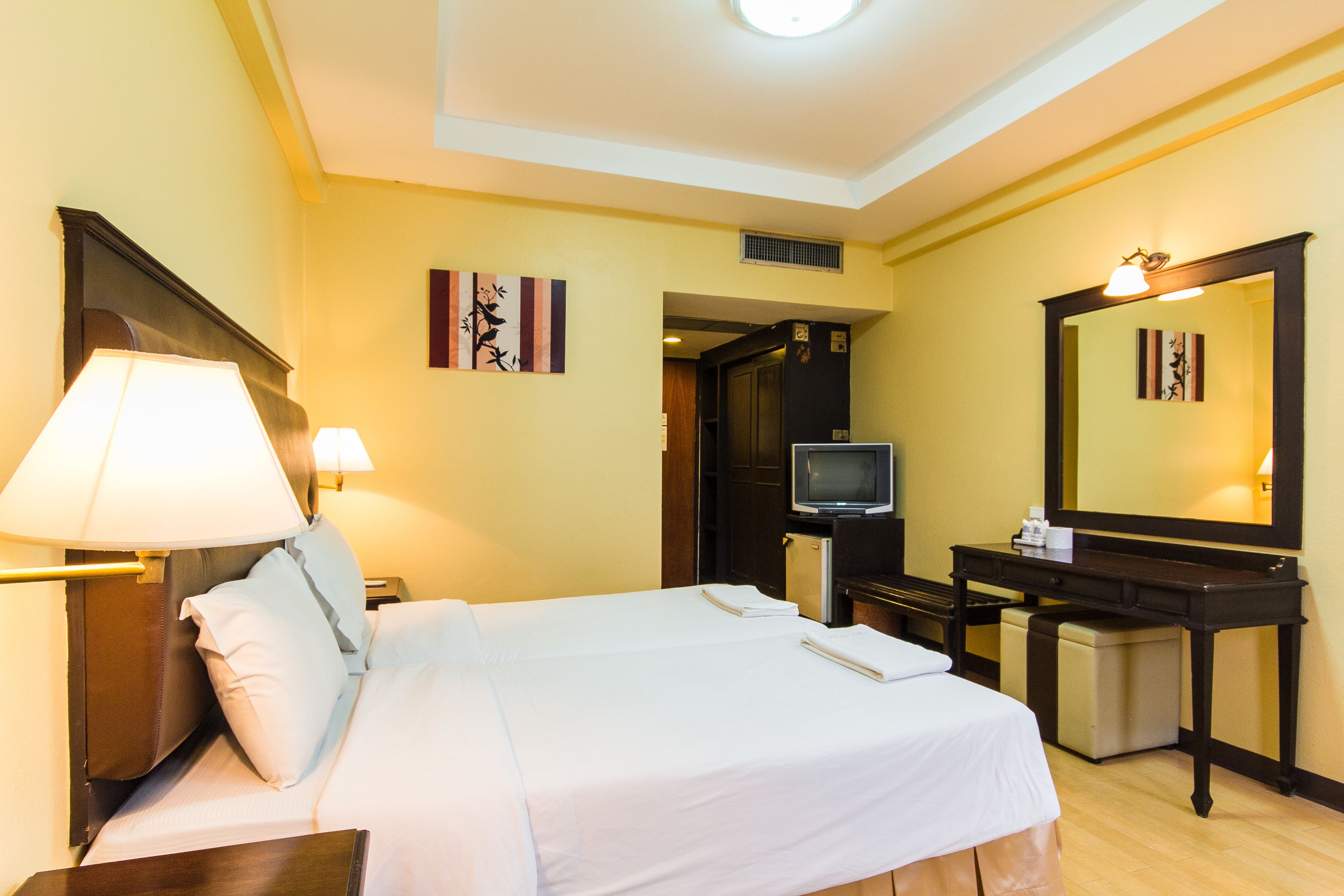 Une chambre d’hôtel avec un grand lit, des lampes de chevet, une télévision, un bureau et un miroir.