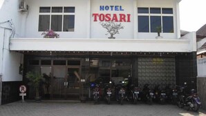 En byggnad med en skylt där det står ”HOTEL TOSARI”, och en rad uppställda motorcyklar framför.
