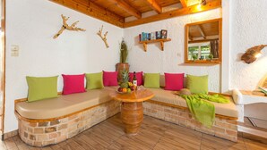 Una habitación acogedora con techo de madera, pared de ladrillo y un banco con cojines de colores.