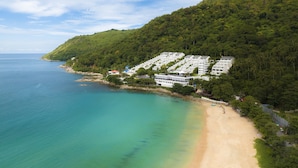 A coastal resort with beachfront villas, a sandy beach, and lush greenery. - The Nai Harn (Rawai)