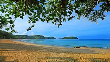 Una playa con aguas azules cristalinas, orilla de arena y exuberante vegetación.