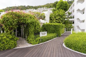 A spa entrance with a wooden pathway, lush greenery, and a sign indicating the spa name.