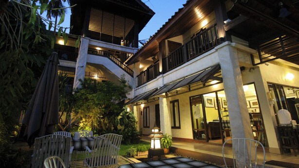 A traditional building with a balcony, outdoor seating, and a well-lit entrance. - Baan Warabordee Hotel (Chiang Rai)