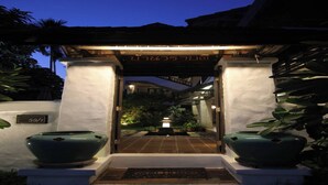 A well-lit entrance with a traditional archway, a pathway leading to a courtyard, and two large planters on either side. - Baan Warabordee Hotel (Chiang Rai)