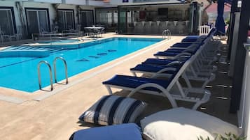 Una piscina al aire libre de temporada, sombrillas, tumbonas