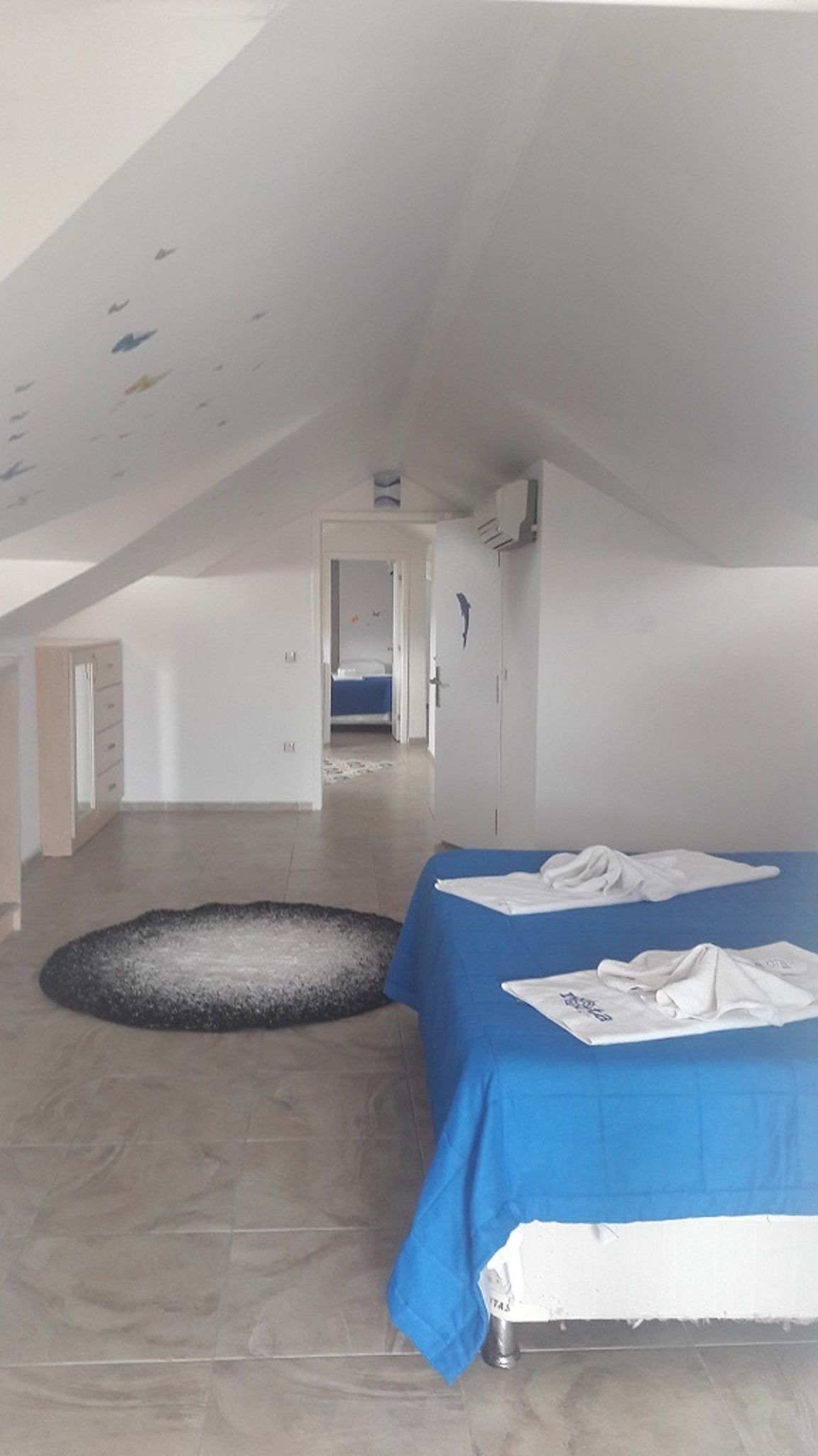 A bedroom with a bed, a small rug, and a ceiling with decorative elements.