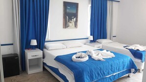 Een hotelkamer met twee bedden, een nachtkastje met een lamp, een kleine prullenbak en een schilderij aan de muur.
