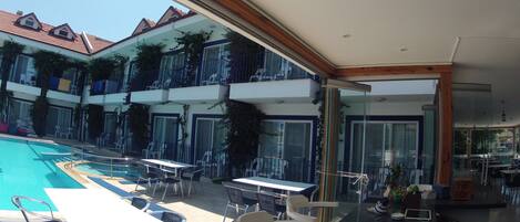 A poolside area with outdoor seating and a view of a multi-story building with balconies.