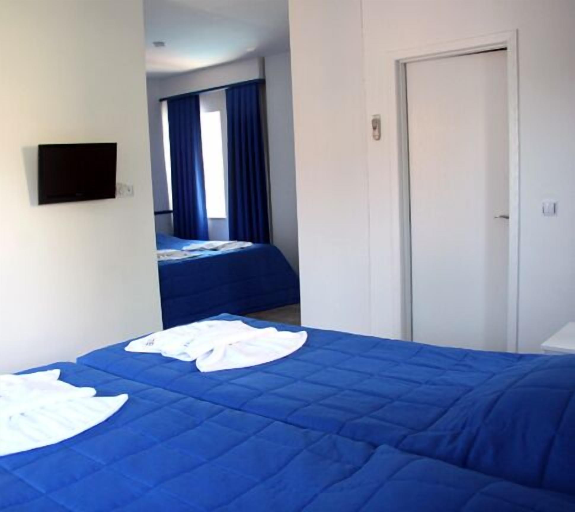 A hotel room with a large bed, a TV mounted on the wall, and a door.