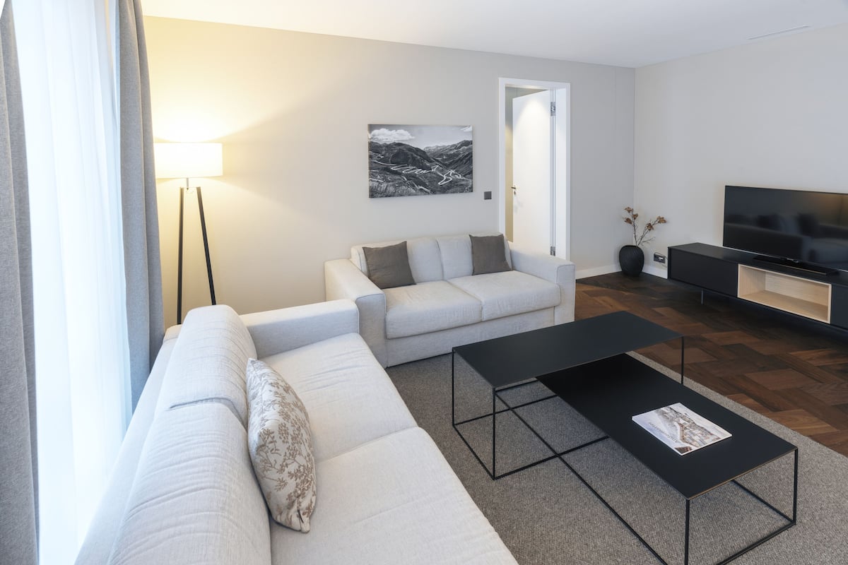 A modern living room with a sofa, a coffee table, a TV, and a lamp.