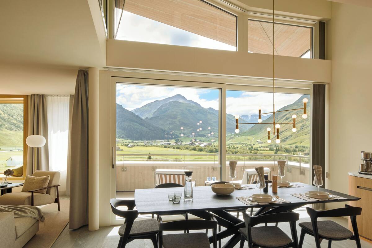 A dining area with a table set for four, a sofa, and a view of mountains.