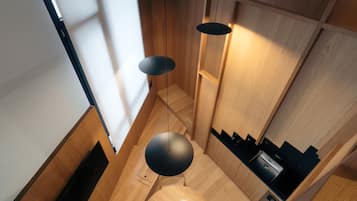 Une cuisine moderne avec des meubles en bois, un plan de travail noir et un luminaire suspendu.