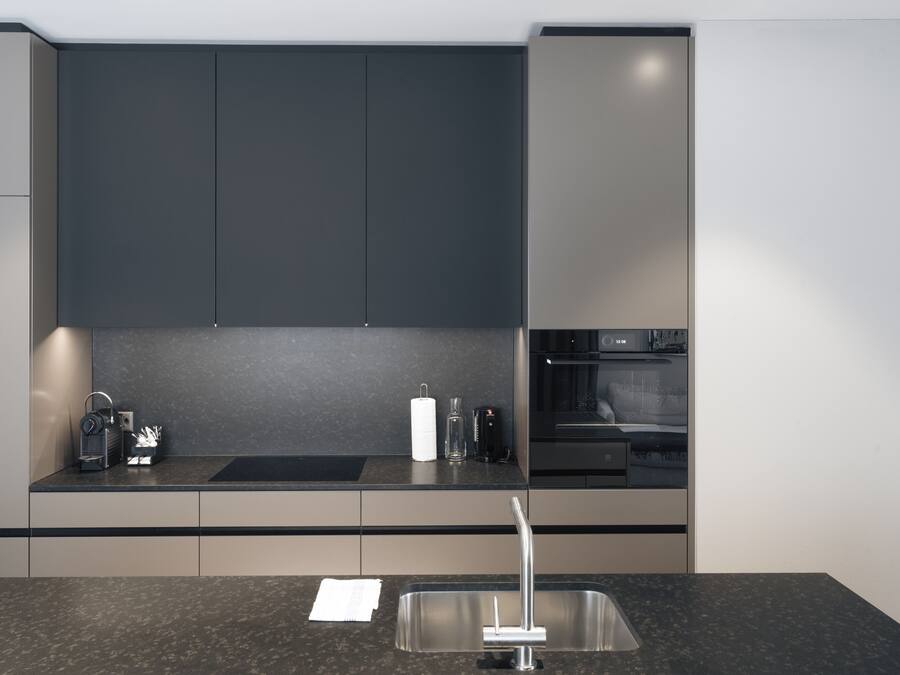 A modern kitchen with dark cabinets, a stainless steel sink, and a built-in oven.