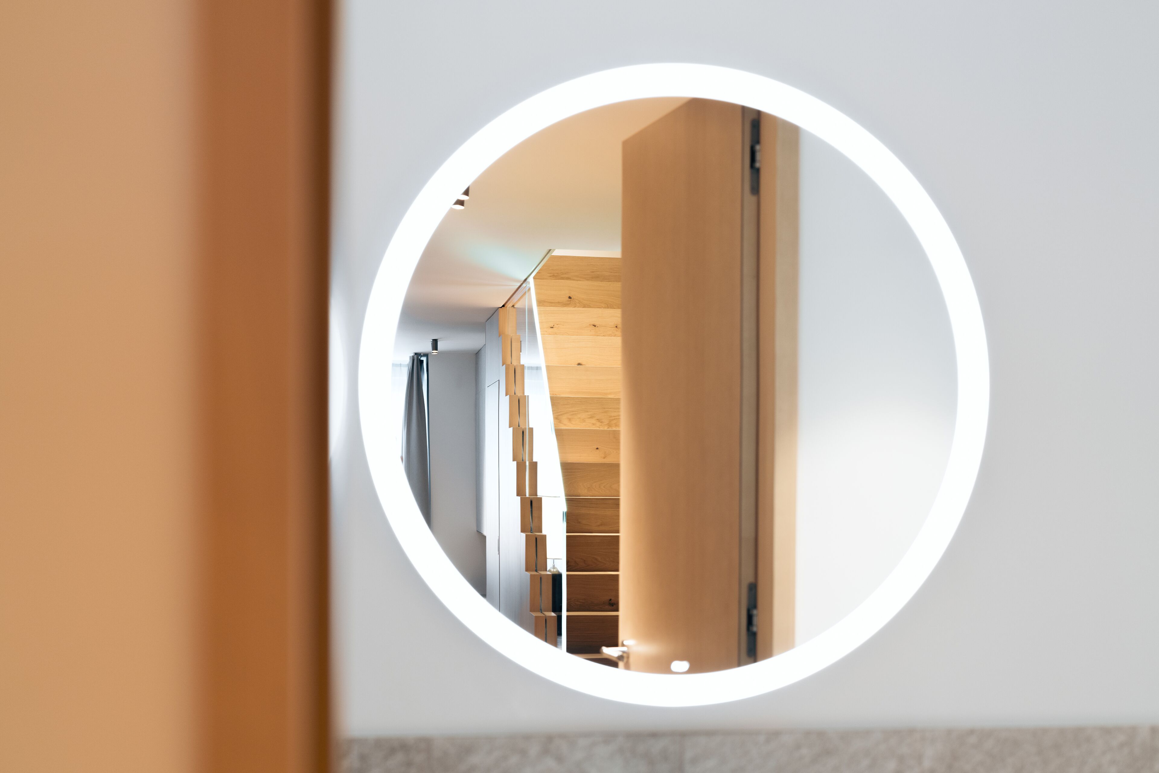 Un miroir rond reflétant un intérieur moderne, avec des éléments en bois et une palette de couleurs neutres.