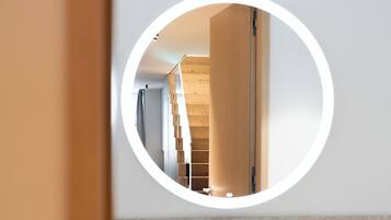 Un miroir rond reflétant un intérieur moderne, avec des éléments en bois et une palette de couleurs neutres.