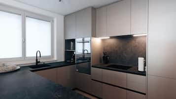 Una cocina moderna con encimeras oscuras, un lavamanos negro y un salpicadero de mármol.