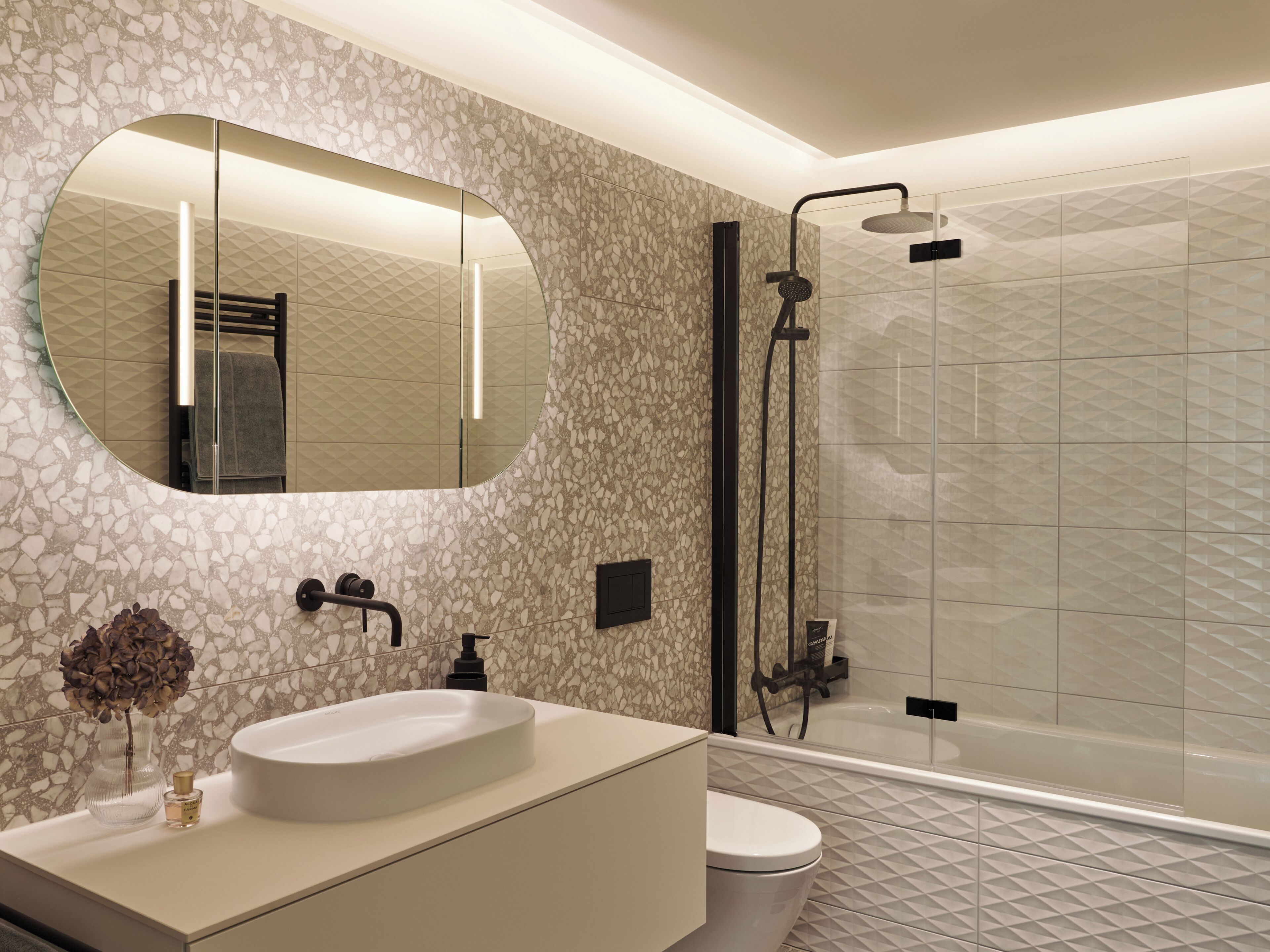 Un baño con un espejo redondo, un lavabo, un inodoro y una zona de ducha.