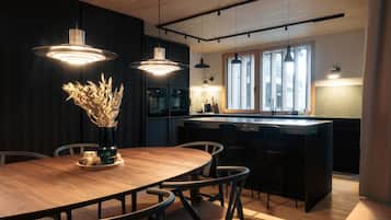Une cuisine moderne avec une table à manger en bois, des luminaires suspendus et une grande fenêtre qui laisse entrer la lumière naturelle.