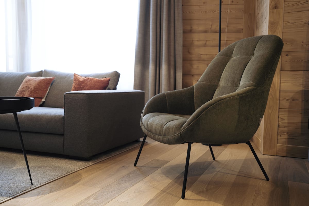 A modern living room with a grey sofa, a green armchair, and a wooden floor.