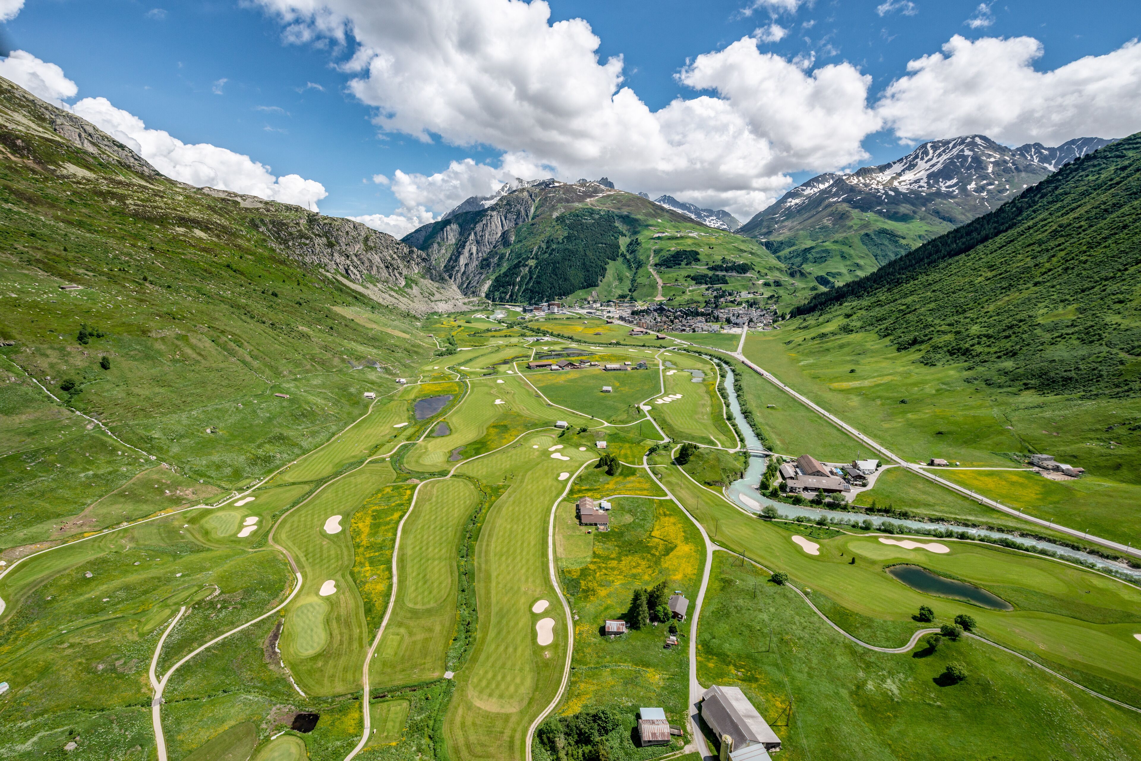 Un campo de golf con búnkeres, obstáculos acuáticos y un club de campo.