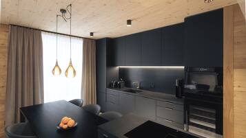 A modern kitchen with a dark countertop, a built-in oven, and pendant lighting.