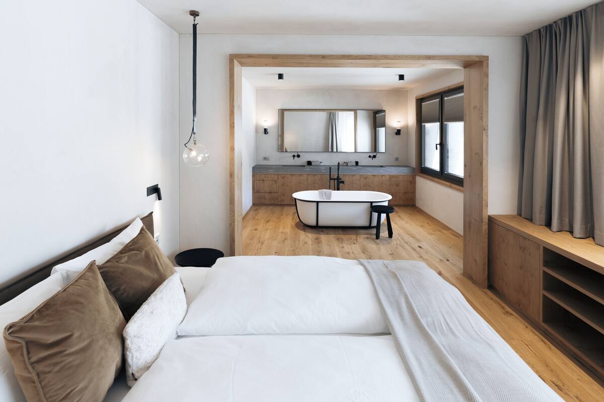 A modern bedroom with a large bed, a wooden headboard, a bedside table, and a built-in bench.