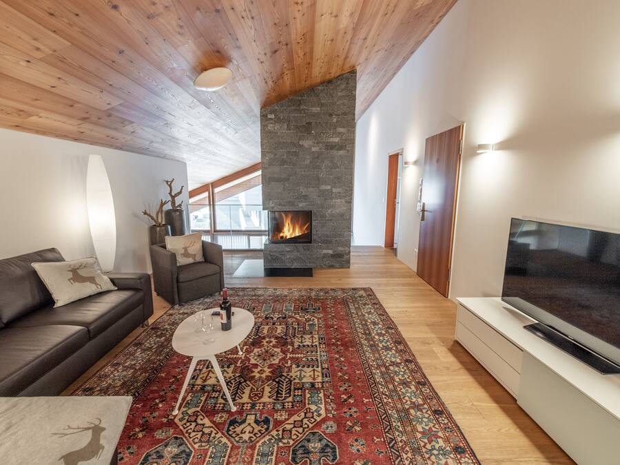 Una sala de estar moderna con chimenea, televisor grande y zona de estar acogedora.