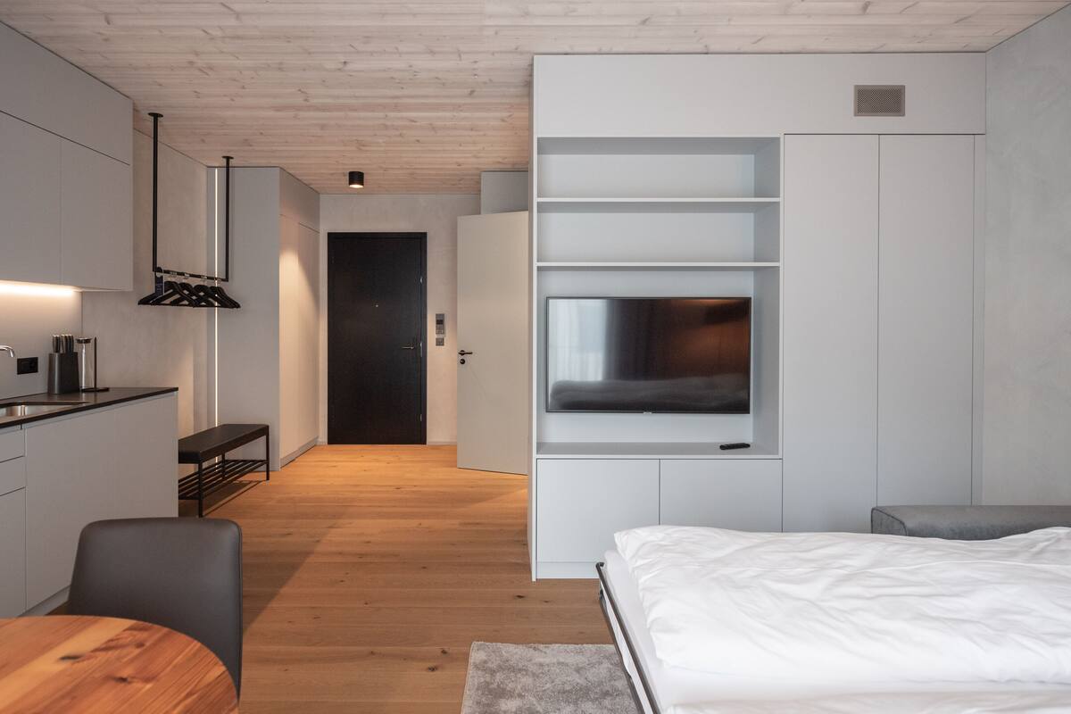 A modern bedroom with a bed, a TV, and a built-in wardrobe.