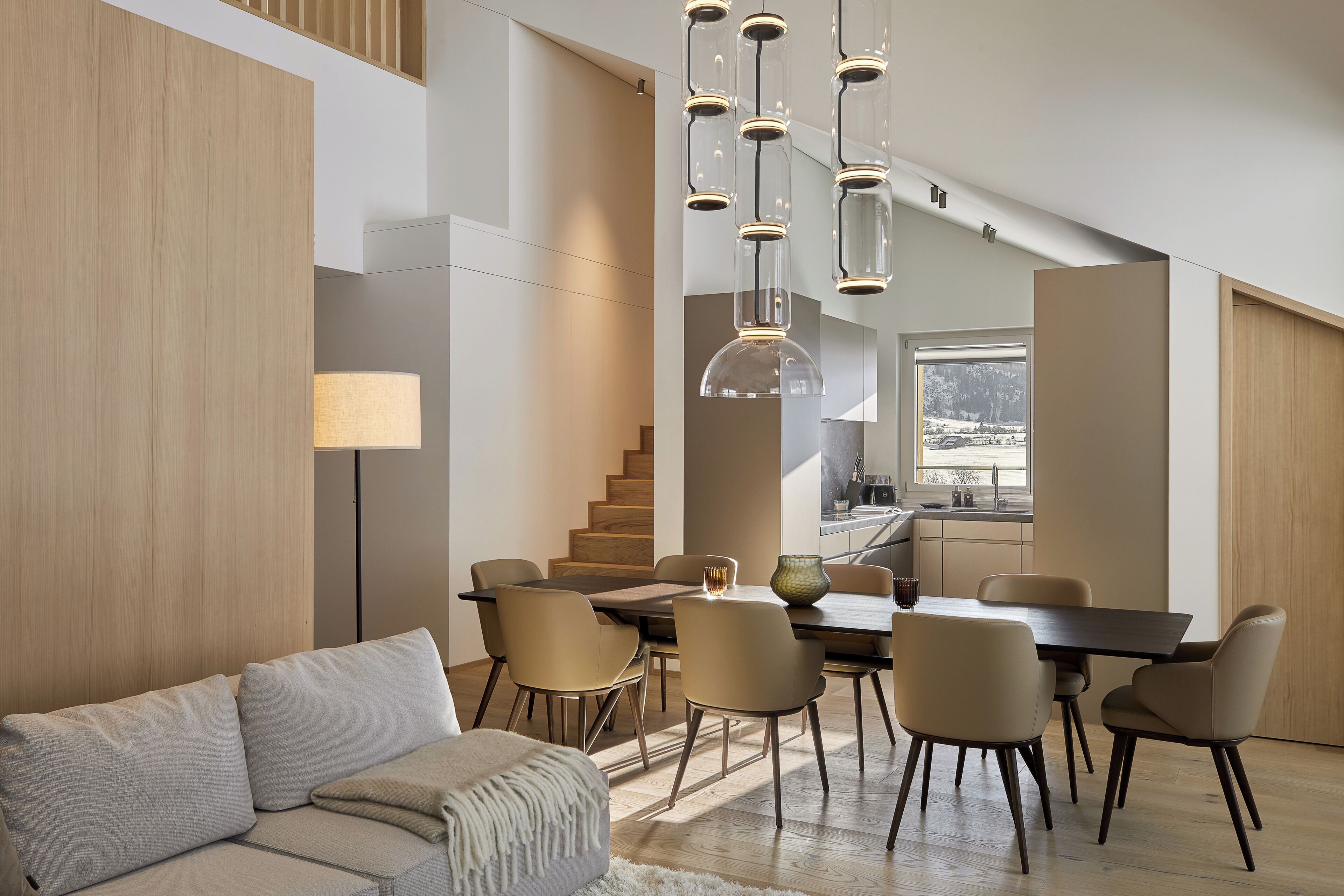 Un intérieur moderne comprenant un coin repas, un canapé et un escalier.